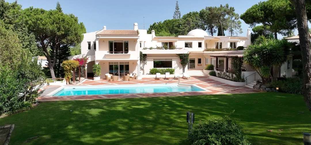 Elegant traditional villa in Quinta do Lago featuring a large private pool, terracotta terrace, and lush garden surroundings.
