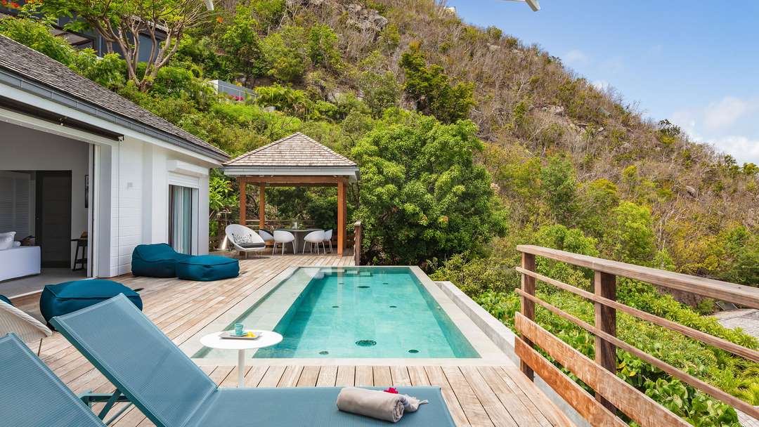 Heated infinity pool and wooden sun deck at Villa Adharra, featuring a covered gazebo for alfresco dining in St. Barths.