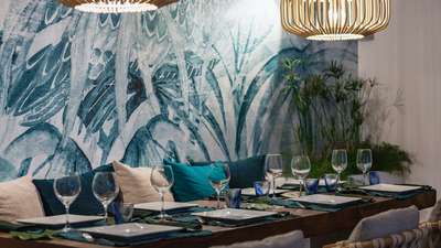 Beautifully set wooden dining table at Villa Adharra, ready for relaxed meals against a stunning tropical wall mural.