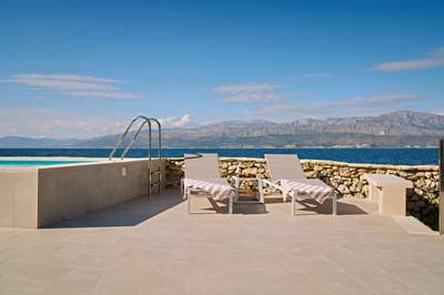 Sun loungers on a stone-paved patio offering unobstructed views of the Adriatic Sea and mountains at Adriatic Edge villa.