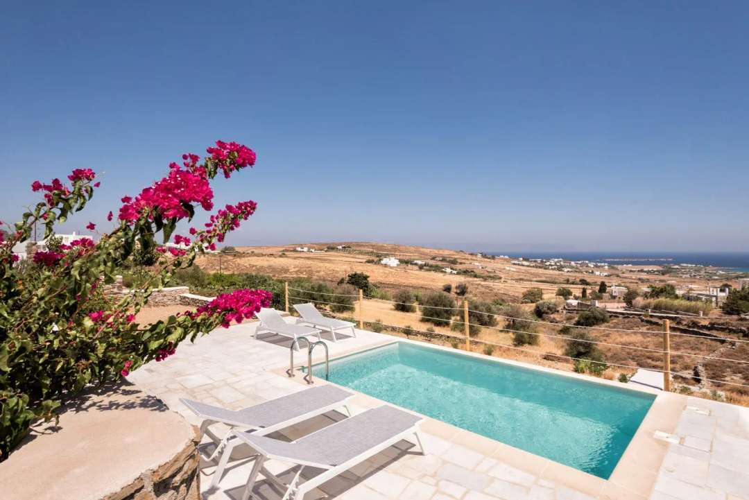 Private plunge pool with sun loungers, vibrant bougainvillea, and panoramic Aegean Sea views at a luxury Cycladic villa.