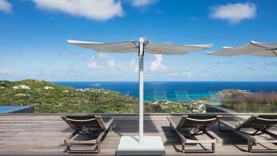 Expansive wooden terrace with luxury sun loungers and parasols facing the breathtaking Caribbean Sea.