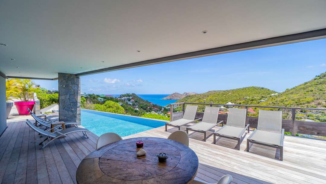 Elegant wooden terrace with lounge chairs, infinity pool, and panoramic ocean views at Villa Alpaka in St Barths.