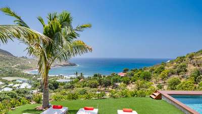 Private heated pool and lush lawn with elegant sun loungers overlooking the breathtaking deep-blue waters of Toiny Bay.