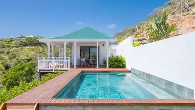 Shimmering private pool and wooden deck leading to a charming covered al fresco dining area at this luxury St. Barths villa.