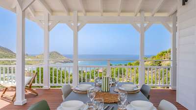 Al fresco dining on a covered balcony at Villa Amalur, offering panoramic ocean views of Toiny Bay in St. Barths.