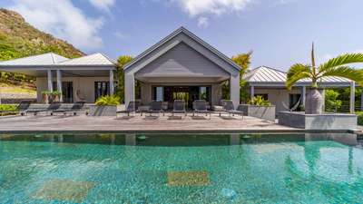 Elegant wooden terrace with sleek sun loungers and a heated infinity pool outside the contemporary main residence.