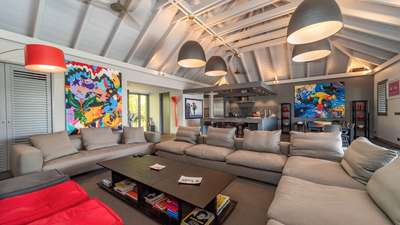 Luxury villa living space with soft grey furnishings, striking contemporary art, and vaulted white ceilings in St. Barths.