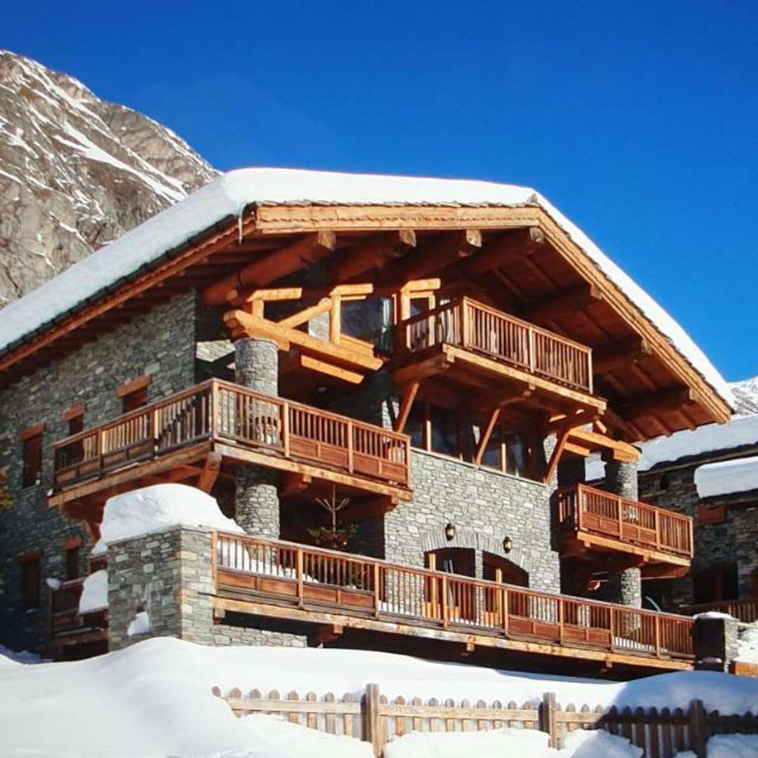 Luxury ski chalet Apartment Le Flocon 3 in Le Fornet featuring stone and wood exterior, balconies, and snowy mountain views.