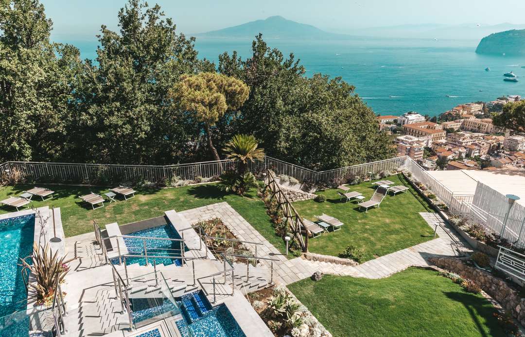 Manicured garden and mosaic-tiled private pool at Villa Artemunda, offering breathtaking views of the Gulf of Naples.