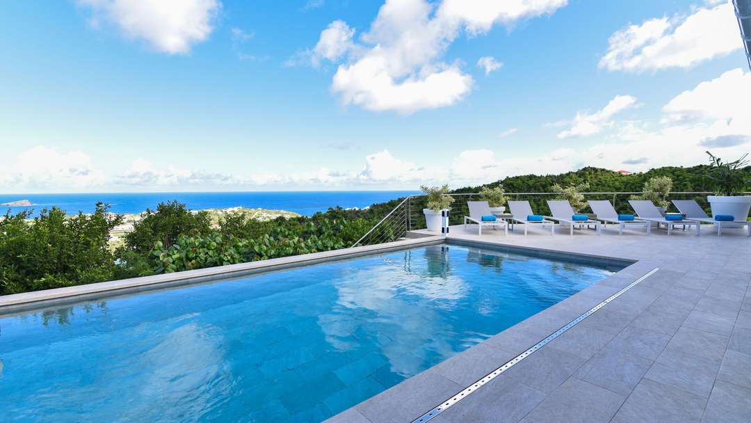 Heated swimming pool and sun loungers on the terrace of Villa Au Coeur Du Rocher, offering panoramic Caribbean Sea views.