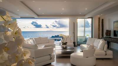 Opulent living room at Villa Axel Rocks offering plush white seating, elegant decor, and sweeping panoramic Caribbean views.