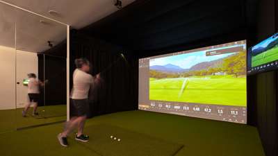 Guest enjoying the state-of-the-art indoor golf simulator within the fully equipped private gym at luxury Villa Axel Rocks.