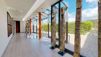 Light-filled entrance of Villa Axel Rocks showcasing unique artistic statues, glass architecture, and a spiral staircase.