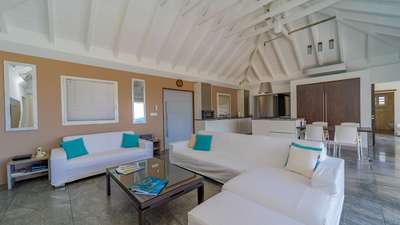Open-concept living and kitchen space in St. Jean with vaulted ceilings, elegant white sofas, and sleek stone flooring.