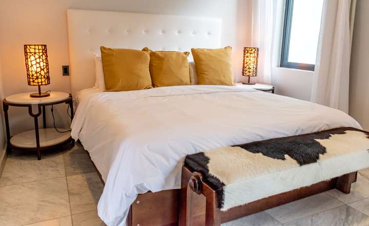 Luxurious bedroom at Beach House 5 featuring a plush king bed, elegant marble flooring, modern lighting, and chic decor.