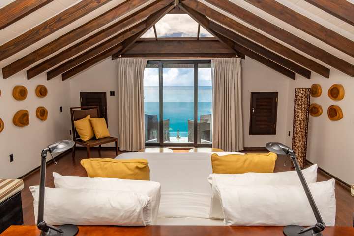 Upper-level Master bedroom at Beach House 5 featuring vaulted wooden ceilings, a king bed, and a private ocean-view balcony.