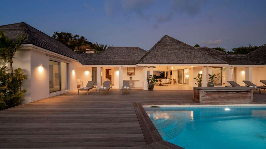 Illuminated private pool and expansive wooden sun deck at Villa Bel Air in St. Barts, offering a serene evening retreat.