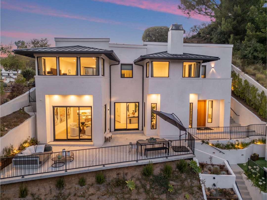 Belden Modern Villa exterior at dusk featuring white modernist architecture, expansive windows, and a spacious outdoor terrace.