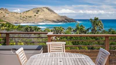 Al fresco dining on the expansive terrace with an exotic wood table and sweeping panoramic ocean views in Toiny.