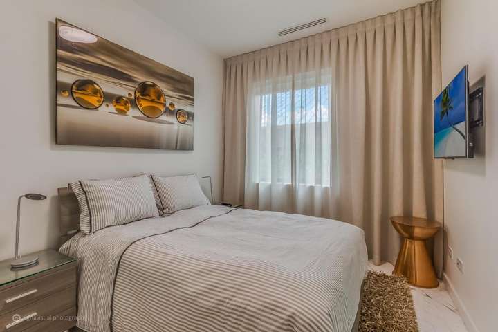Elegant guest bedroom with modern furnishings, premium linens, and contemporary artwork in a luxury Miami villa rental.