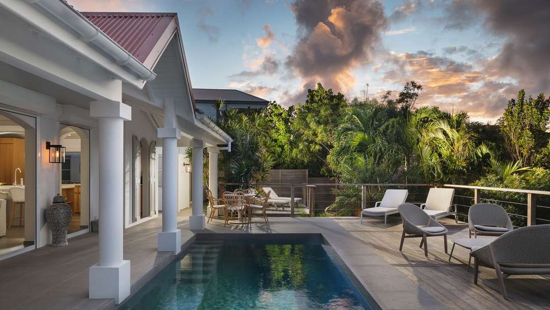 Private heated pool and sun deck at luxury Villa Bijou in St. Barts, surrounded by lush tropical gardens at sunset.