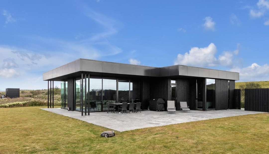 Modern Nordic Black Tee Villa exterior with a sleek black facade, expansive glass windows, and a spacious outdoor terrace.