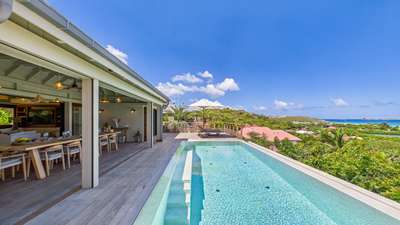 Pristine heated infinity pool with convenient steps leading to a covered dining terrace and sweeping St-Jean Bay views.