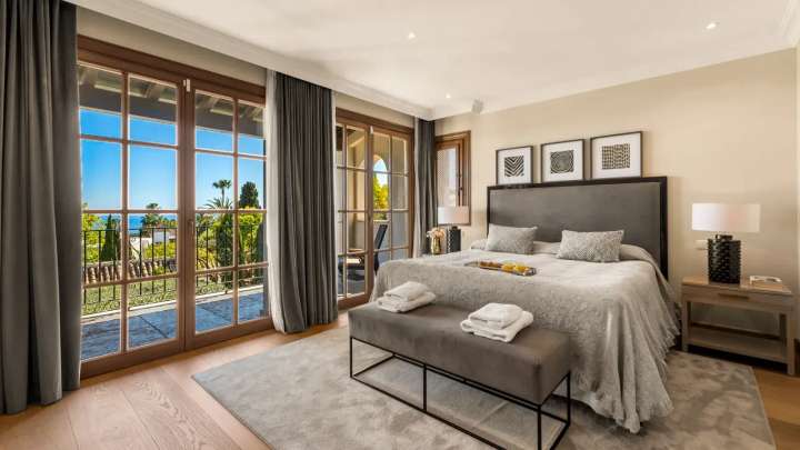 High-end bedroom opening onto a private balcony with stunning Mediterranean Sea and garden views at Golden Carolina villa.
