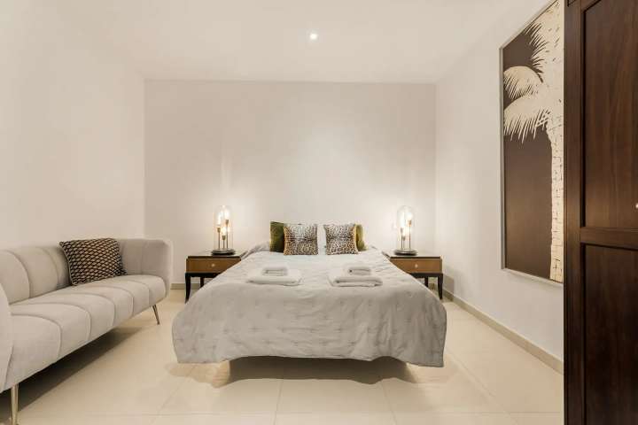 Chic modern bedroom featuring a comfortable double bed, elegant grey sofa, and minimalist design at this Golden Mile villa.
