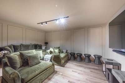 Luxury basement cinema room at Emerald Lines, featuring plush green velvet seating, a large screen, and full sound system.