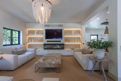 Elegant living room at Emerald Lines, featuring plush sofas, a built-in TV, modern fireplace, and backlit shelving.