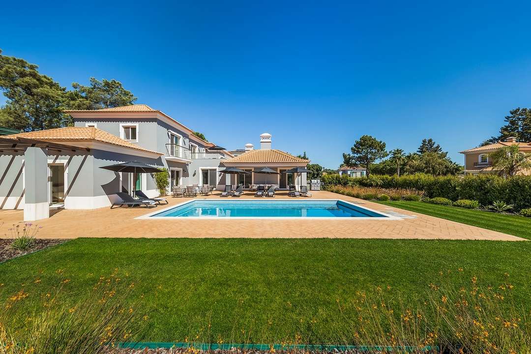 Luxury Casa do Encosta villa exterior featuring a private pool, manicured lawn, and elegant architecture in Quinta do Lago.