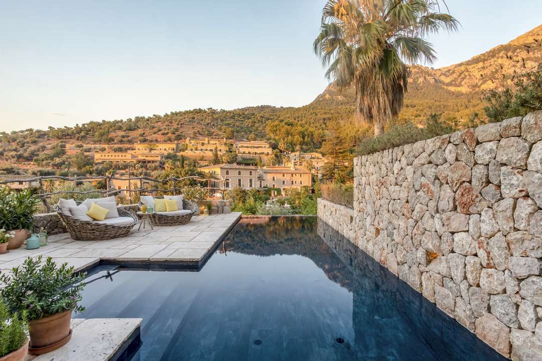 Infinity pool on a stone terrace at Casa Noelia, offering breathtaking views of Deia village and the Tramuntana Mountains.