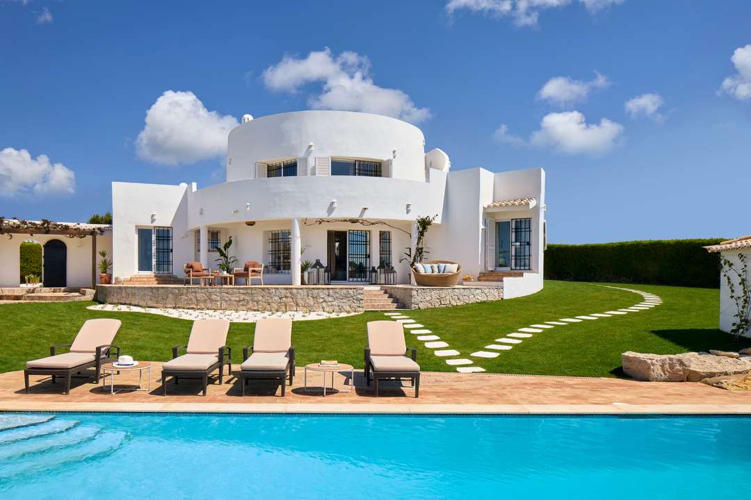 Elegant restored windmill villa in the Algarve with a private heated pool, sun loungers, and lush manicured gardens.