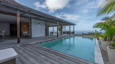 Seamless indoor-outdoor living at Casa Tigre with a covered wooden terrace, heated infinity pool, and panoramic ocean views.