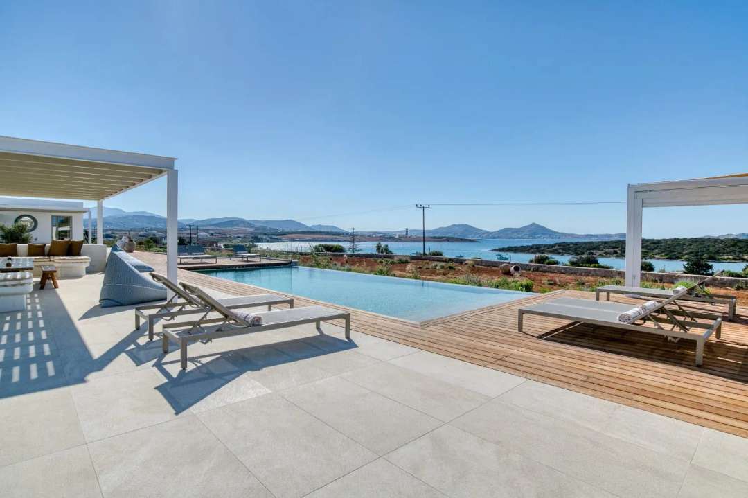 Stunning infinity pool at Paros Gaze featuring a wooden deck, elegant sun loungers, and sweeping Aegean Sea views.