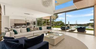 Luxurious living room with floor-to-ceiling glass doors offering panoramic sea views and access to the infinity pool.