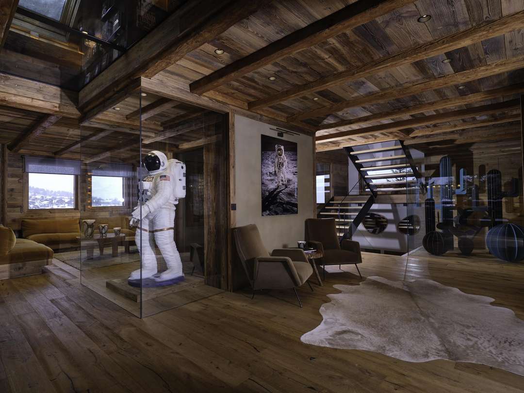 Expansive living area at Chalet Apollo featuring rustic wood beams, modern seating, and a unique glass-enclosed astronaut.