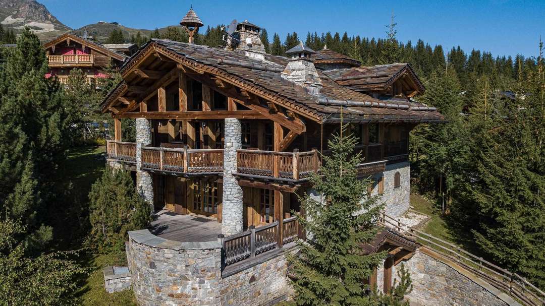 Exterior of luxury Chalet Everest in Courchevel 1850, featuring traditional timber and stone architecture amidst pine trees.