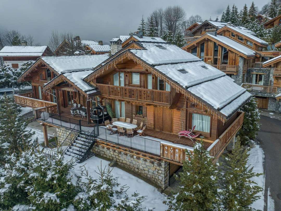 Aerial view of Chalet Lady Mijane's elegant wooden exterior in winter, featuring a spacious terrace and snowy mountain views.