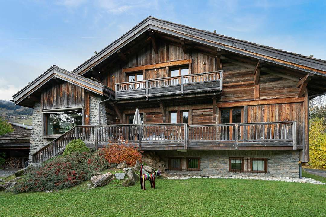 Traditional alpine wooden exterior of Chalet Mozart in Megève, featuring spacious balconies, stone details, and garden views.