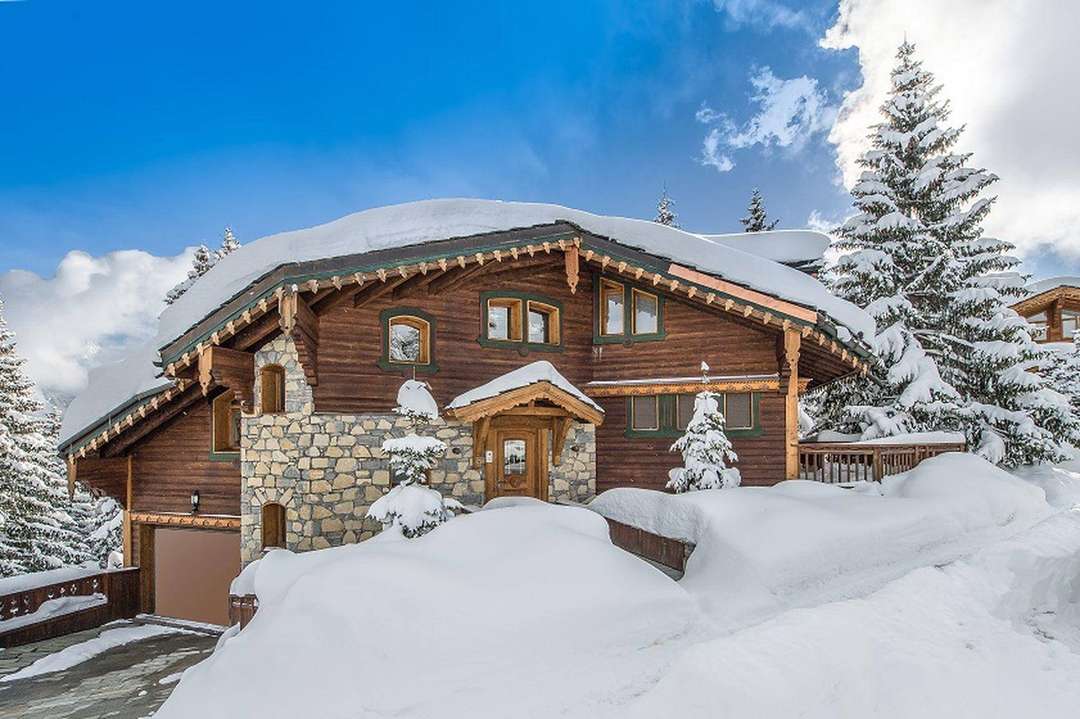Classic Alpine architecture at Chalet Rossignol, featuring rustic wood, stone details, and snowy Courchevel mountain views.