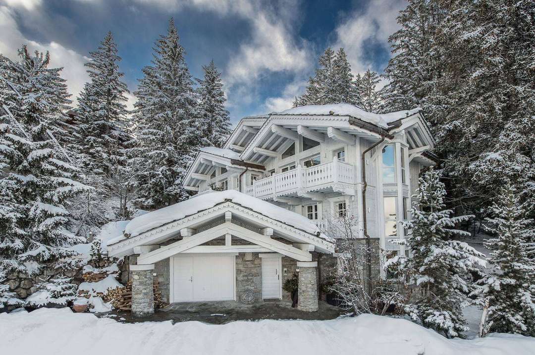 Chalet White Dream's striking all-white exterior surrounded by snow-covered pines in the heart of Courchevel 1850.