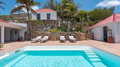 Relaxing sun loungers on the terracotta terrace surrounded by tropical gardens and stone walls at Villa Chant De L'océan.