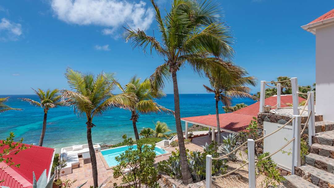 Exterior stone staircase from Bedroom 3 leading to the pool and terrace with ocean views at Villa Chant De L'océan.