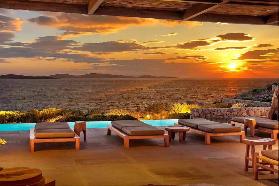 Elegant shaded terrace with wooden sun loungers offering sweeping sunset views over the Aegean Sea at Villa Chantal.