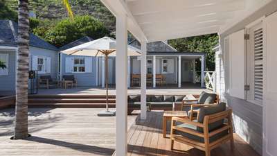 Expansive wood terrace at Villa Citron Vert featuring plush lounge seating, an umbrella, and elegant Caribbean architecture.