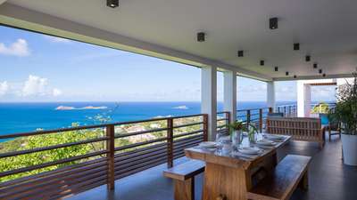 Sophisticated alfresco dining on the covered terrace, featuring a solid wood table and endless panoramic ocean views.