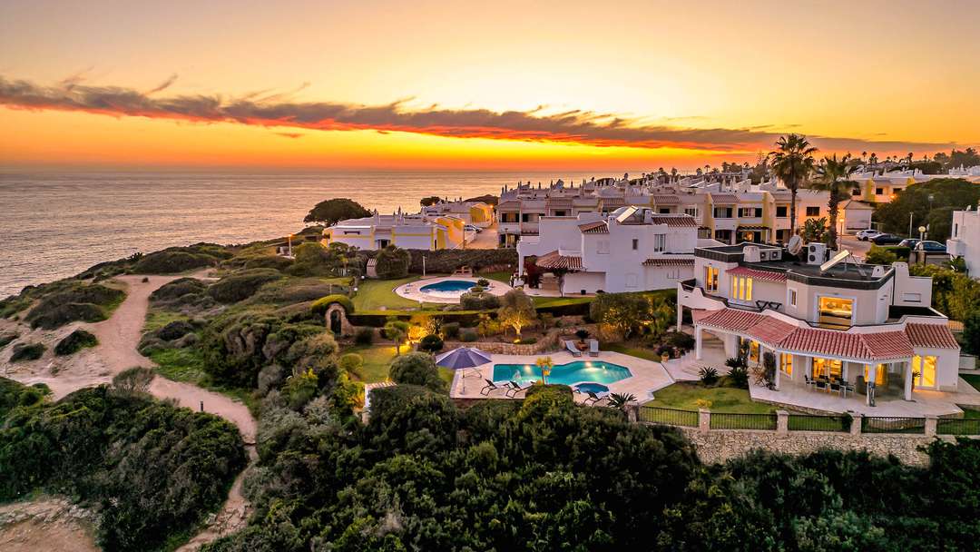 Aerial sunset view of Cliffs of Benagil villa, showcasing the private pool, manicured gardens, and panoramic Atlantic views.